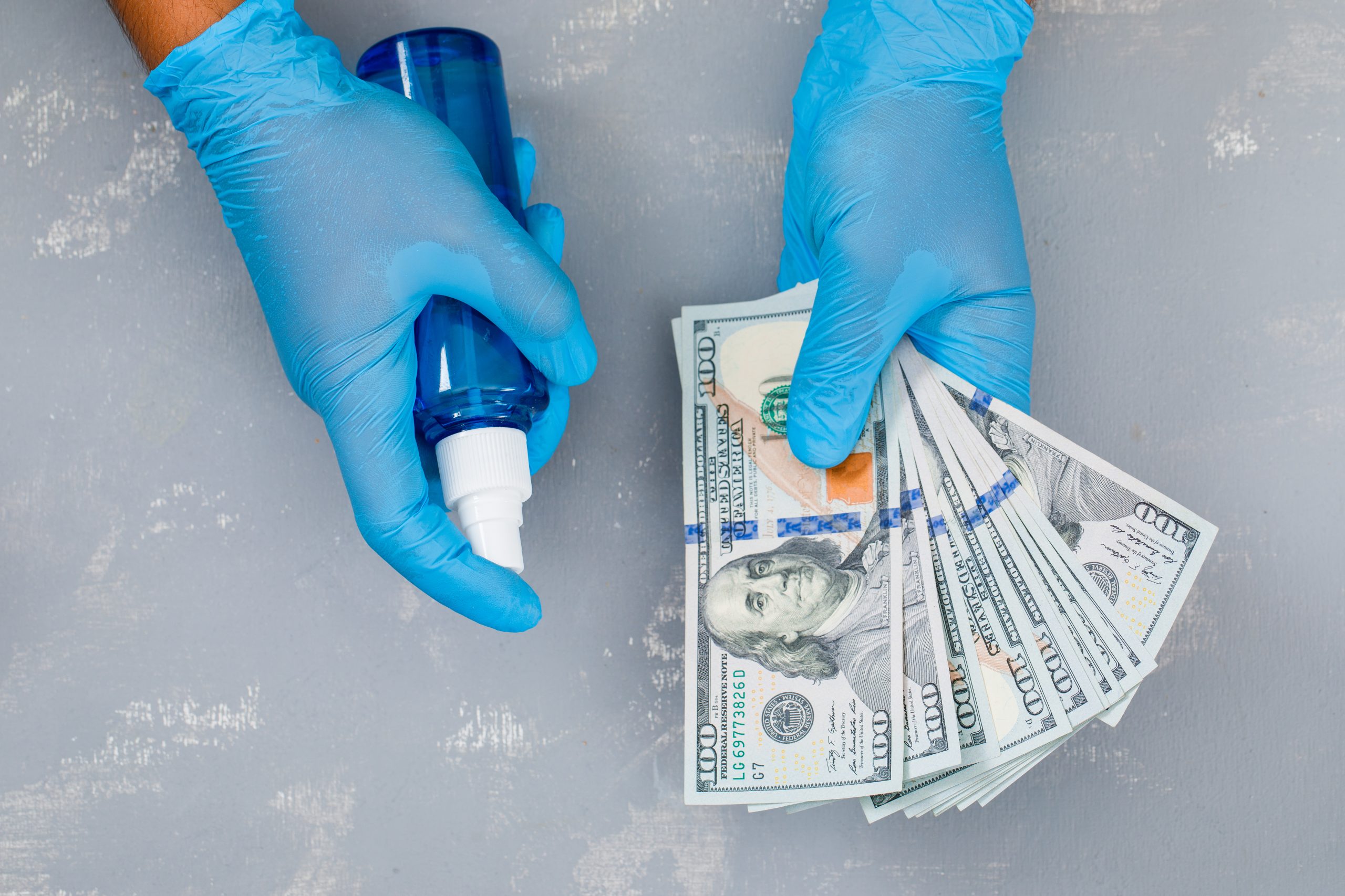 Pandemic prevention concept on plaster background flat lay. man spraying sanitizer on banknotes